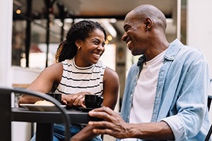 Couple smiling while enjoying cup of coffee outside