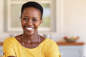 Woman in yellow shirt smiling at home