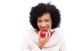older woman biting into a red apple