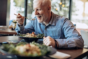 a man with dentures enjoying a healthy meal