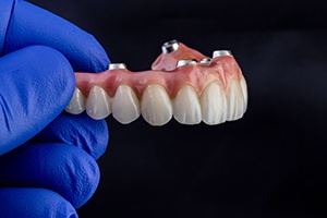 a close-up of a dentist holding an implant denture