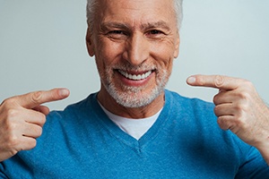 a patient smiling and pointing to his teeth