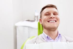 Male dental patient sitting in chair and smiling