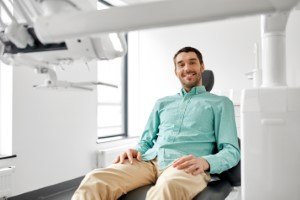 Male dental patient in green shirt smiling in chair