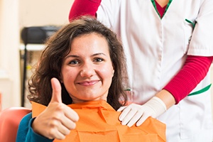 Woman in dental chair giving thumbs up