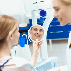 A woman looking at her smile in the mirror