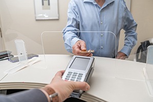 A man paying the cost of teeth whitening