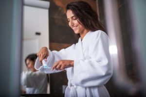 person squeezing toothpaste and their toothbrush