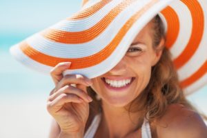 Woman in sun hat smiles after teeth whitening in Michigan City