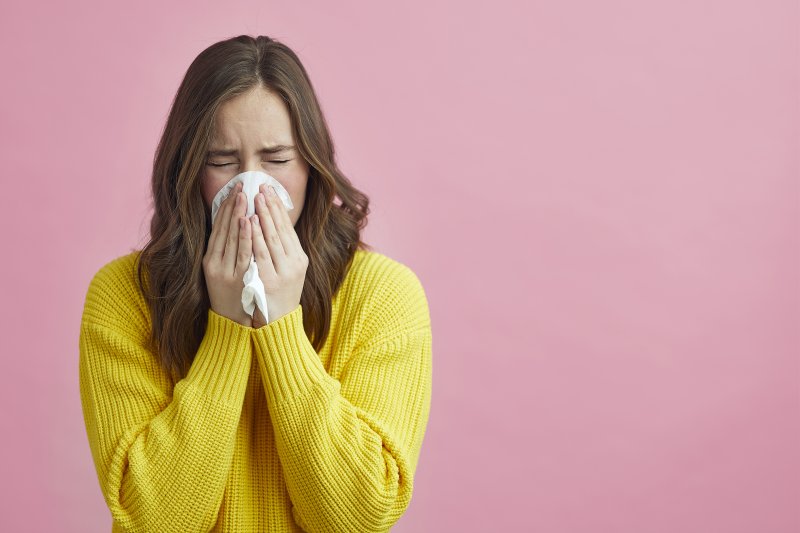 Woman with allergies blowing her nose into tissue