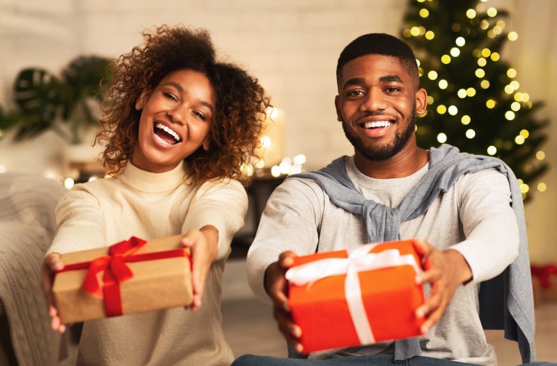 Young couple smiling and holding out presents